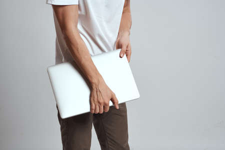 A man with a laptop in his hands on a light background in a white t-shirt emotions light background new technologiesの写真素材
