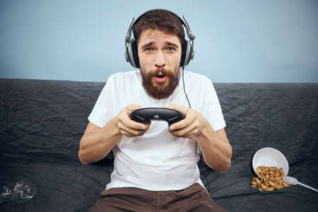 Man sitting on sofa wearing headphones with gamepadの写真素材