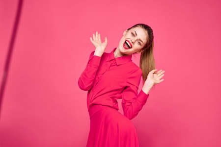 Woman on a pink background in fashionable clothes and bright makeupの写真素材