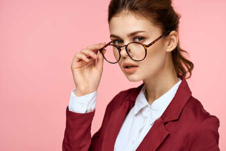 Elegant woman in red jacket glasses office manager pink backgroundの写真素材