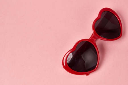 Heart shaped sunglasses with red frames on a pink backgroundの写真素材