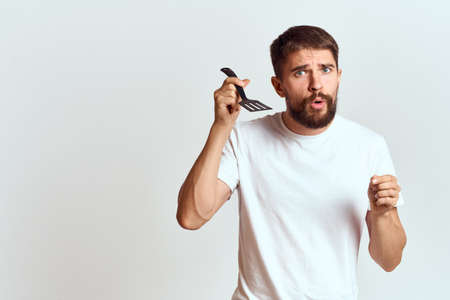man with cooking shovel and white t-shirt close-up cropped view emotion gesturing with handの写真素材