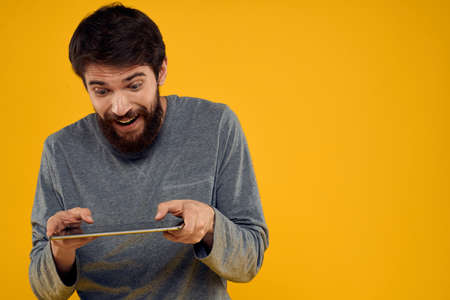 Bearded man with tablet in hands technology work wireless device yellow background