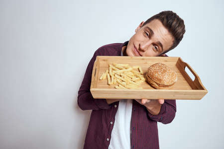 Man eating wooden pallet fast food french fries hamburger diet food restaurant light backgroundの写真素材