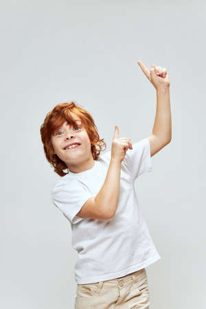 Cheerful red-haired boy smile index fingers on top gestures with hands Copy Spaceの写真素材