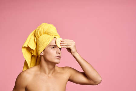 man with a towel on his head and a yellow sponge in his hand cosmetic procedure clean skin of the...