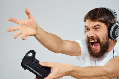 Man in headphones with gamepad playing hobby entertainment lifestyle light background