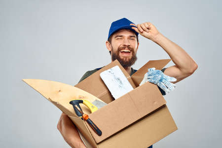 man in work uniform with box in hands tools lifestyle light backgroundの写真素材