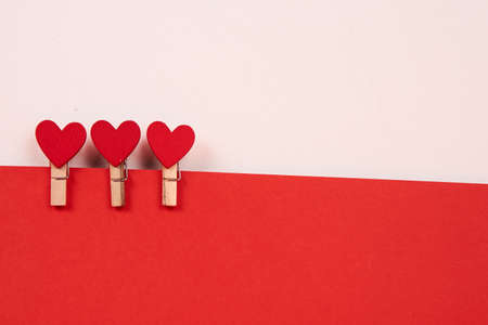 Wooden clothespins with red hearts on a sheet of paper light background
