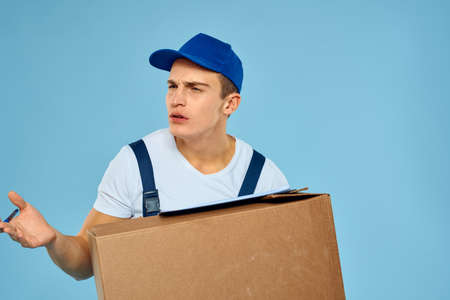 Man worker with cardboard box delivery loader lifestyle blue backgroundの写真素材