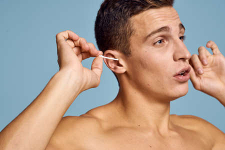 Guy with ear sticks and nude torso cropped view blue backgroundの写真素材