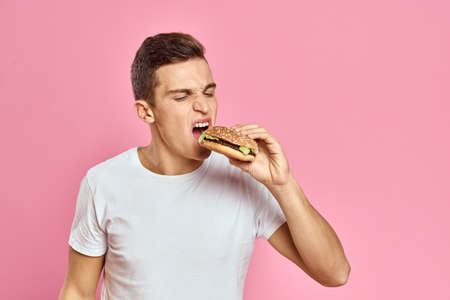 man with big hamburger on pink background calories fast food cropped view Copy Space close-up
