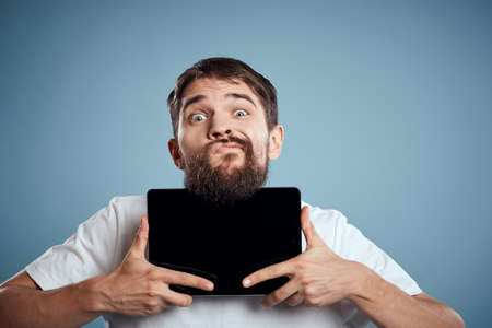 man with tablet near face on blue background cropped view touch monitor new technologies Copy Spaceの写真素材