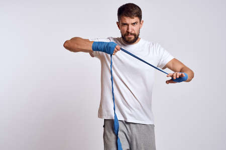 sports man in white t-shirt blue boxing bandages on his arms workout exercises
