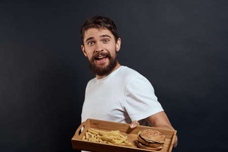 Woman man with pallet of fast food fries and hamburger diet food restaurant white t-shirt dark backgroundの写真素材
