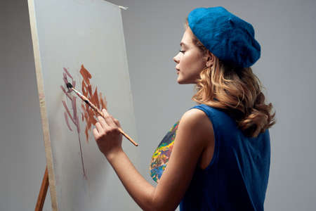 woman artist in blue beret palette easel drawing art creative hobby gray backgroundの写真素材