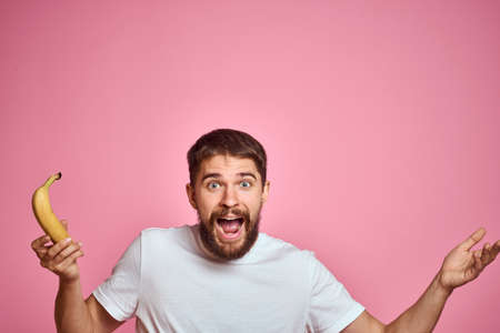 bearded man with banana in hand on pink background fun emotions model