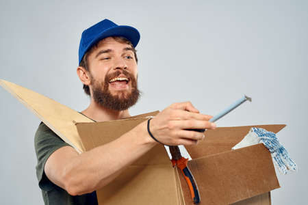 man in work uniform with box in hands tools lifestyle light background