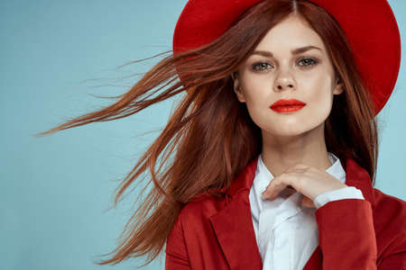 Beautiful woman in red hat jacket red lips long hair charm blue backgroundの写真素材