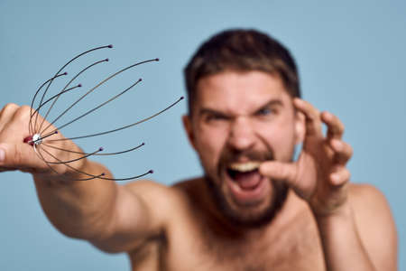 Man with naked shoulders head massager healthy lifestyle blue backgroundの写真素材