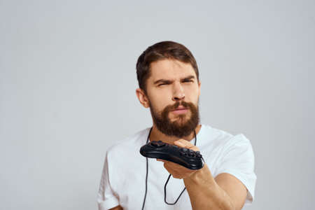 A man with a joystick in his hands fun games lifestyle white t-shirt light background