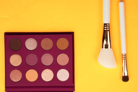 Eyeshadows and makeup brushes on a yellow background top view professional cosmeticsの写真素材