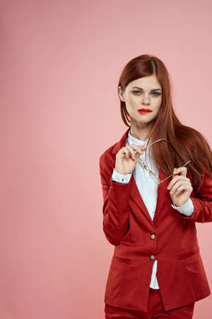 woman in red jacket with glasses red lips long hair pink backgroundの写真素材