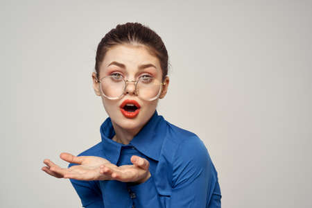 Portrait of emotional woman in blue shirt and glasses bright makeup model light background cropped...