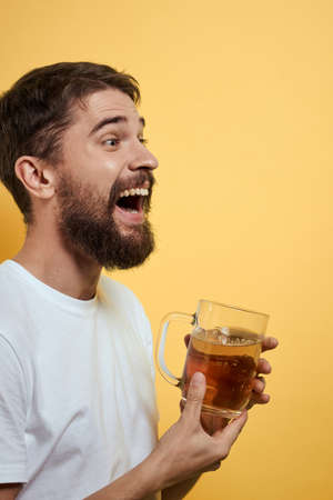 Man with a mug of beer fun alcohol lifestyle white t-shirt yellow isolated background