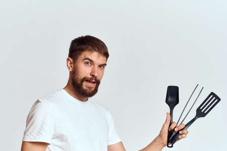 A man with kitchen appliances in the hands of their white T-shirt on a light background cropped viewの写真素材