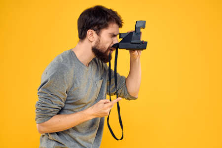 Male photographer with professional photo camera. Professional Creative approach studio yellow...