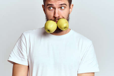 Energetic man with apples health vitamins diet and lifestyle white t-shirt cropped viewの写真素材