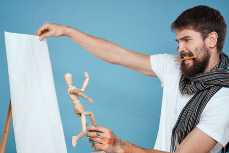 Male artist with a wooden dummy in hands drawing Creative hobby blue backgroundの写真素材