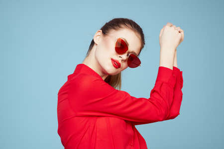 Woman with dark glasses red lips charm shirt studio blue backgroundの写真素材