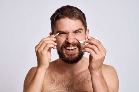 Bearded man with bare shoulders cotton swabs hygiene body careの写真素材