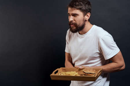 Woman man with pallet of fast food fries and hamburger diet food restaurant white t-shirt dark backgroundの写真素材