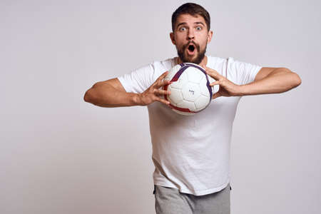 Male coach with a soccer ball in his hands on a light background energy explanation of movementsの写真素材