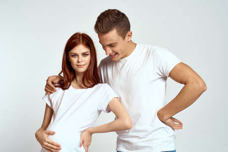 a pregnant woman and a young man are waiting for a baby on a light background emotions family love