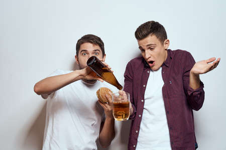 Two cheerful friends drinking beer drunk fun lifestyle communication light backgroundの写真素材