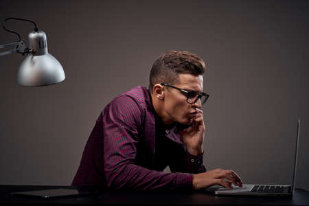 Male manager is sitting at the table and talking on the phone open laptop working office room