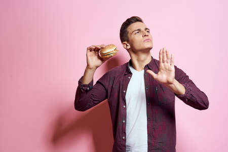 hungry man with hamburgers in hands fast food diet food emotions pink backgroundの写真素材