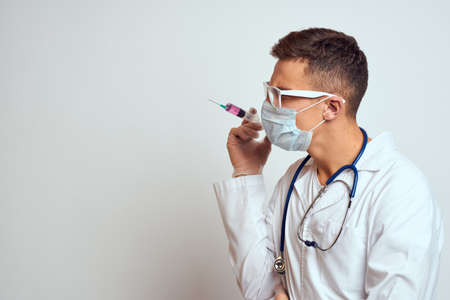 doctor in a medical gown with a stethoscope and glasses on a light background cropped view portraitの写真素材