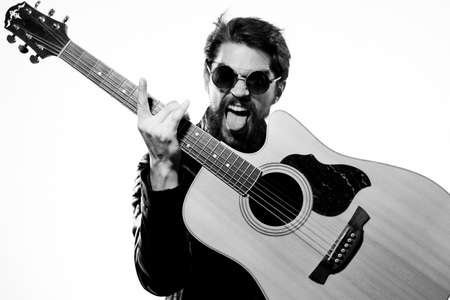 A man holds a guitar in his hands music emotions black leather jacket dark glasses studio light...
