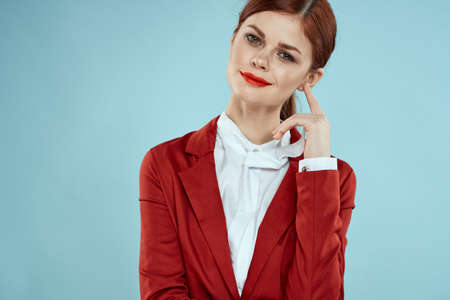 Elegant woman in red jacket bright makeup lips self-confidence cropped view blue backgroundの写真素材