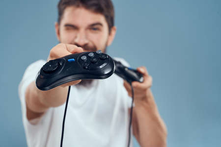 man holding gamepads games lifestyle technology console emotions white t-shirt blue background