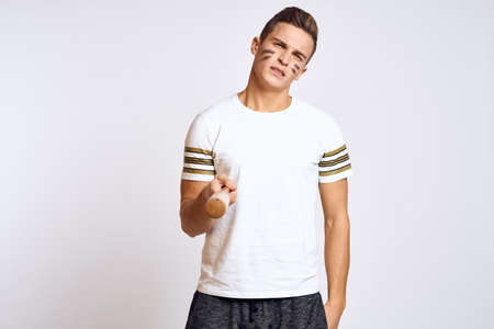 a man with a baseball bat on a light background exercises kicks sport ball model