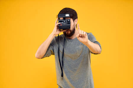 Male photographer with professional photo camera. Professional Creative approach studio yellow backgroundの写真素材