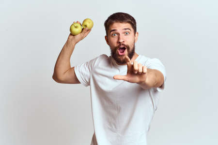 Energetic man with apples health vitamins diet and lifestyle white t-shirt cropped viewの写真素材