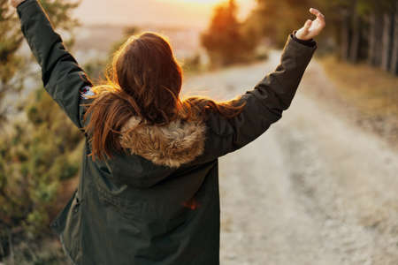 Woman in a jacket with raised up hands fresh air Freedom rear view natureの写真素材