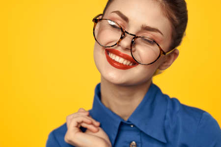 A woman in a blue shirt and glasses with bright makeup on her face is gesturing with her hands Copy Spaceの写真素材